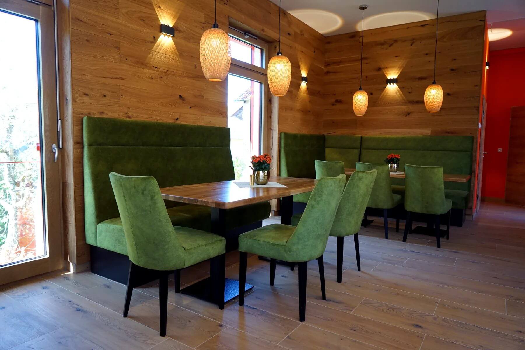 Gastraum im Cafe Flow mit Polsterbank, Holztischen und gruenen Gastronomiestuehlen