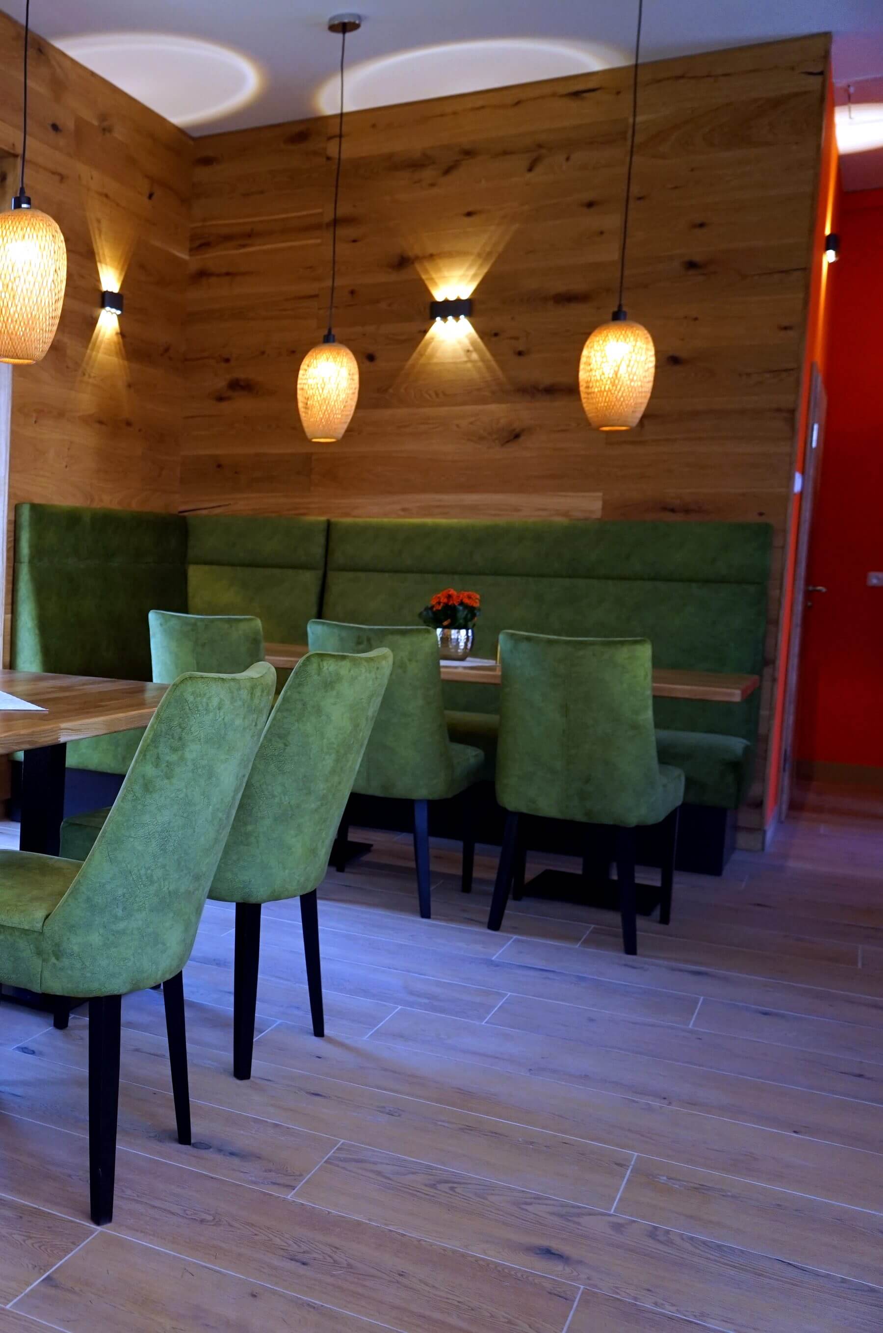 Sitzgruppe im Cafe Flow mit Holzwand, Pendelleuchten, Polsterbank und Gastronomiestuehlen